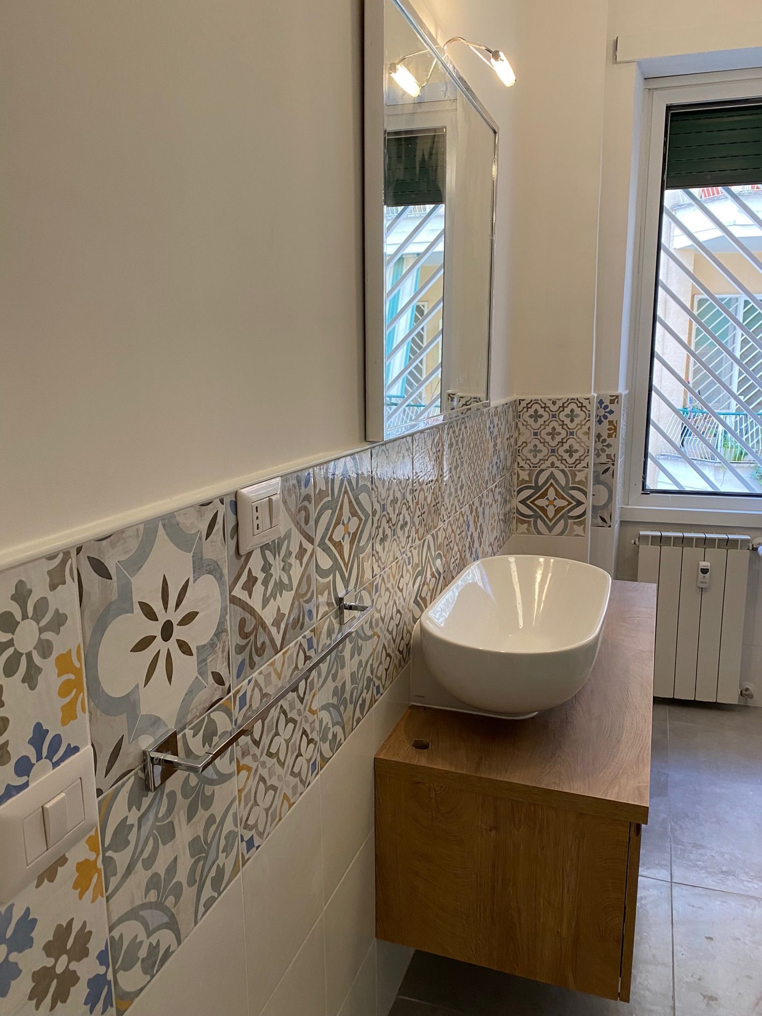 Un bagno con lavandino, specchio e finestra.