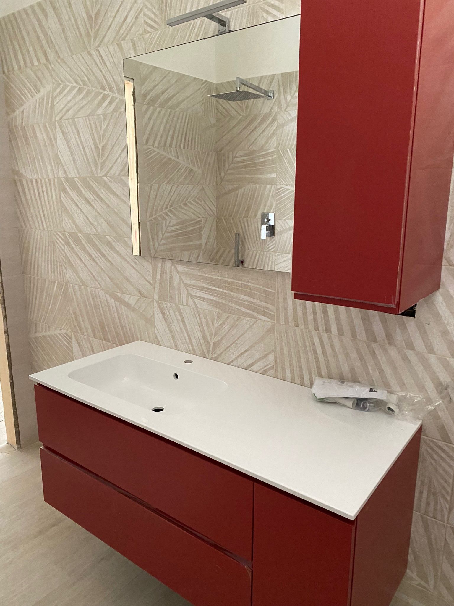 Un bagno con lavandino, specchio e armadietti rossi.