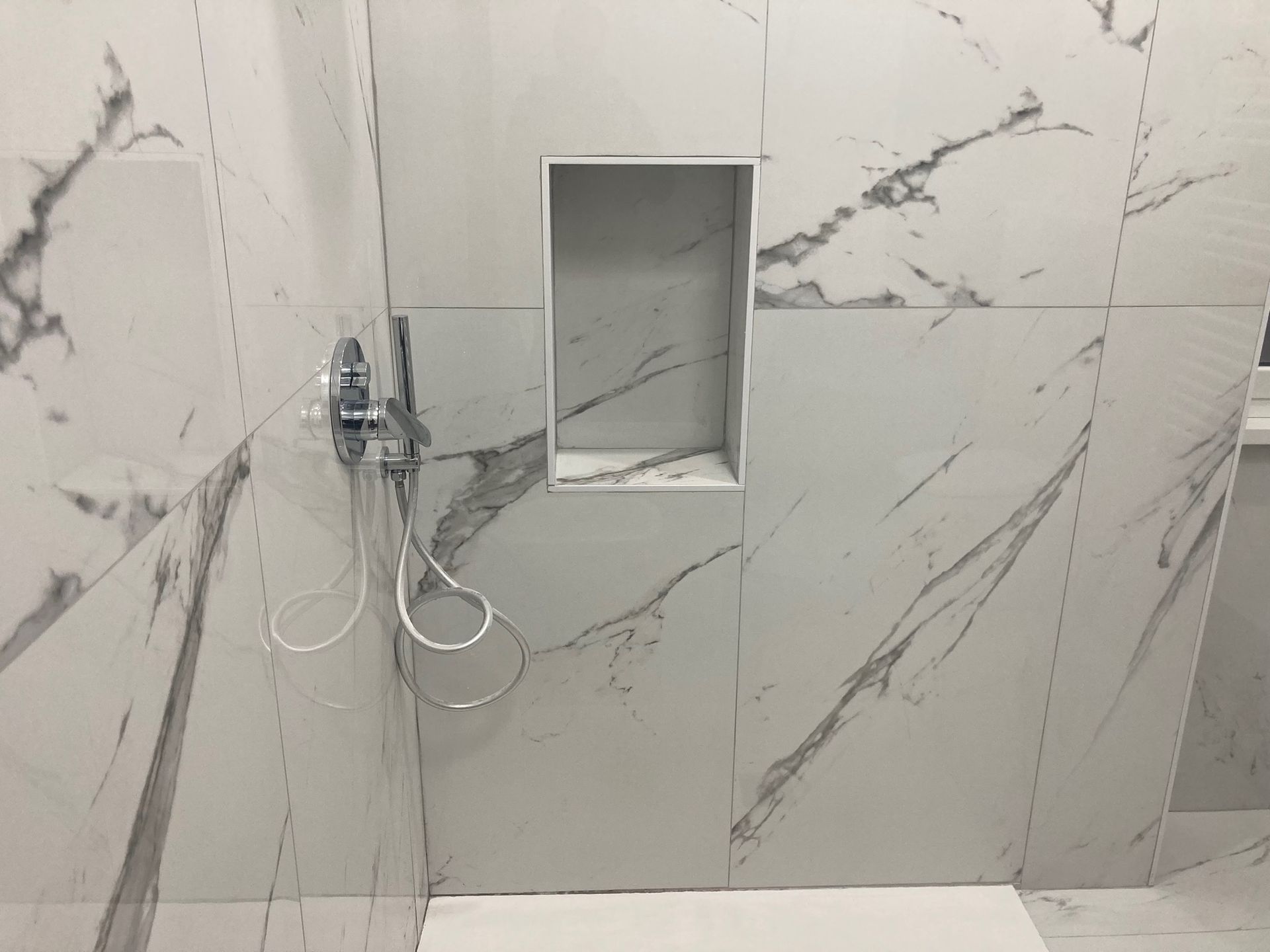 Un bagno con piastrelle di marmo e soffione doccia.