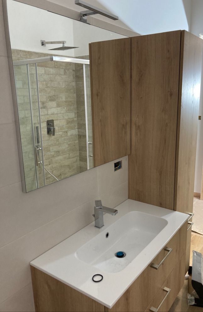 Un bagno con lavandino, specchio e armadietti.