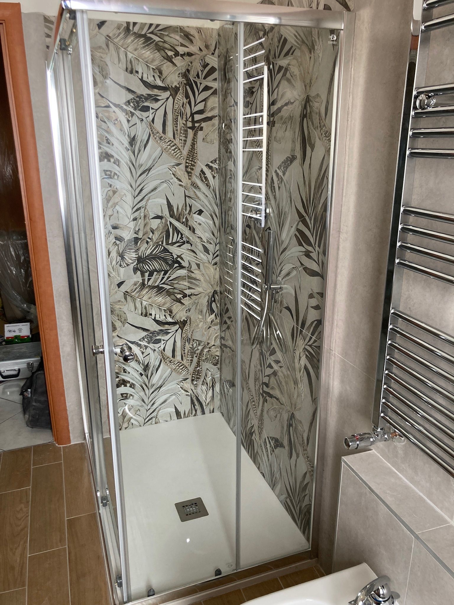 Un bagno con porta doccia scorrevole in vetro e portasciugamani.