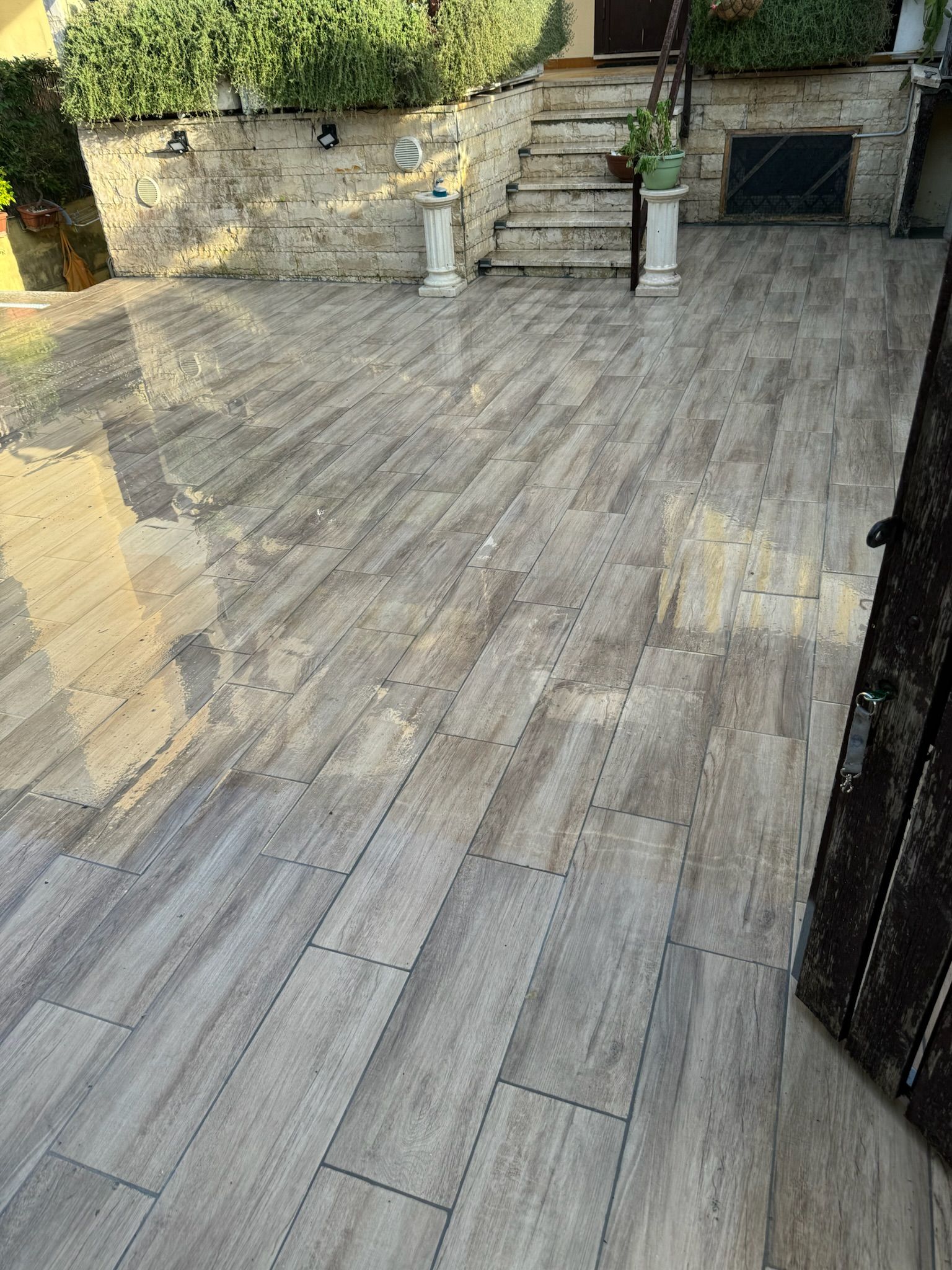 Un patio con pavimento in legno e scale sullo sfondo.