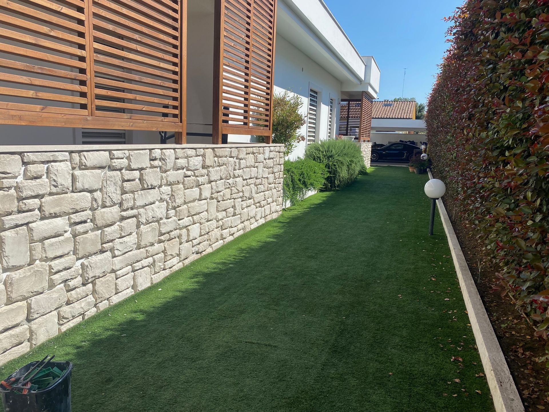 Un muro di pietra circonda un prato verde lussureggiante di fronte a una casa