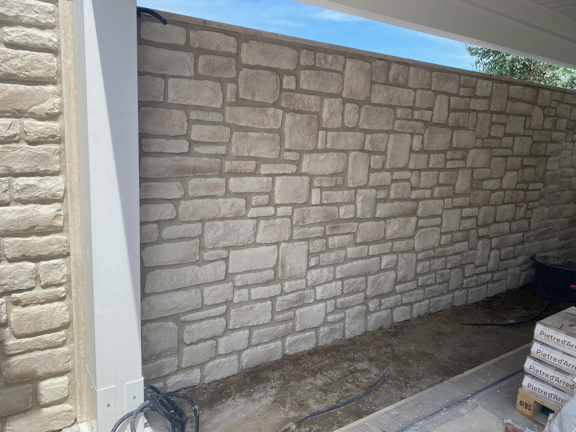 Un muro di mattoni viene costruito accanto a una casa.