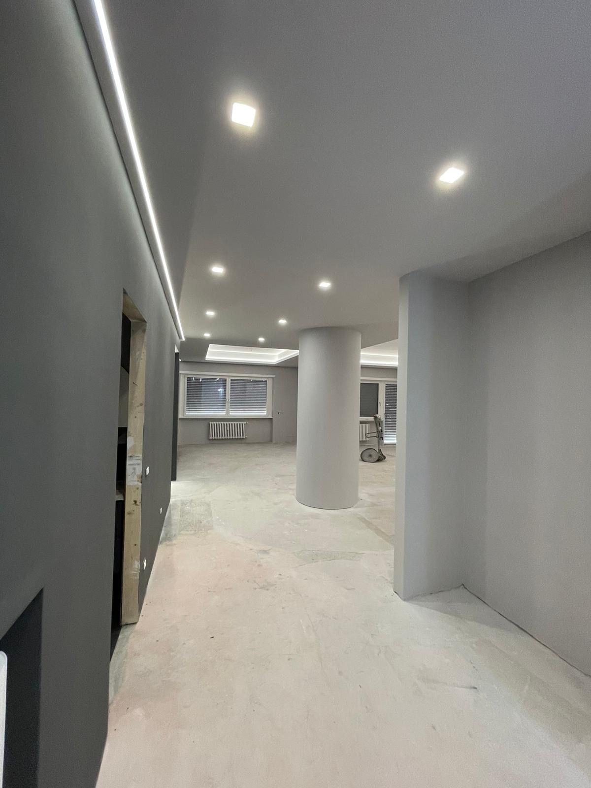 Un lungo corridoio con colonne e una lampada a soffitto.