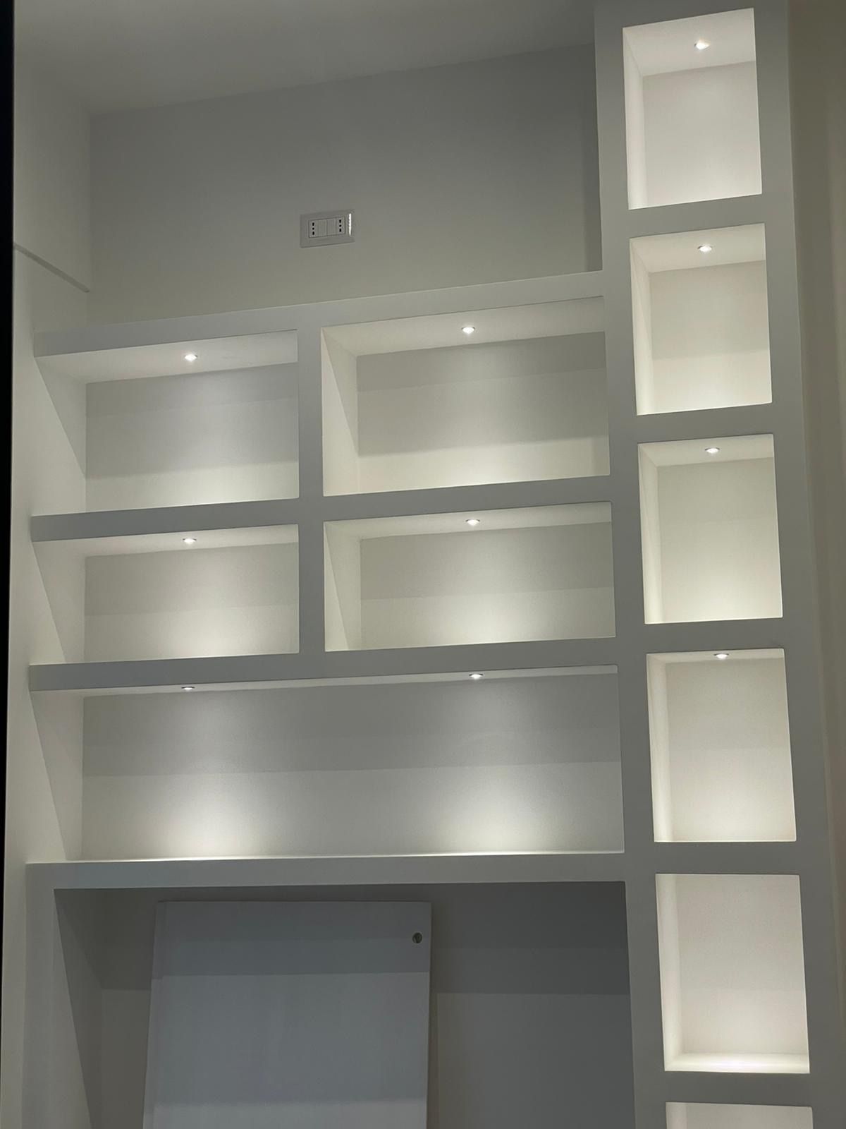 Una fila di scaffali bianchi con luci su di essi in una stanza