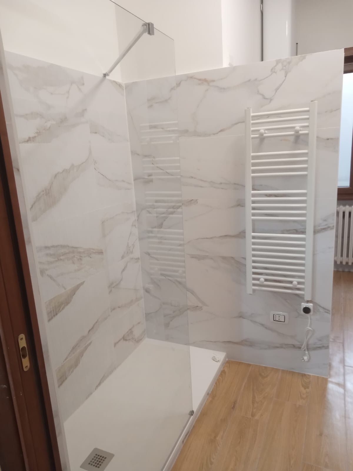 Un bagno con cabina doccia e portasciugamani.