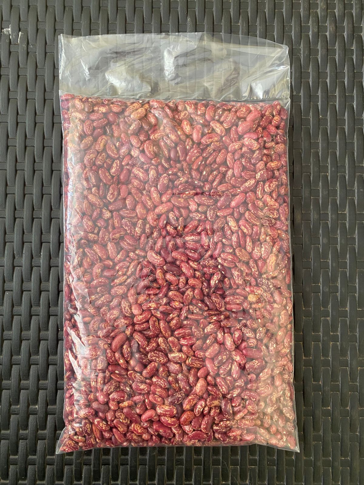 Bolsa de frijoles rojos y tostados sobre una superficie oscura similar al mimbre.