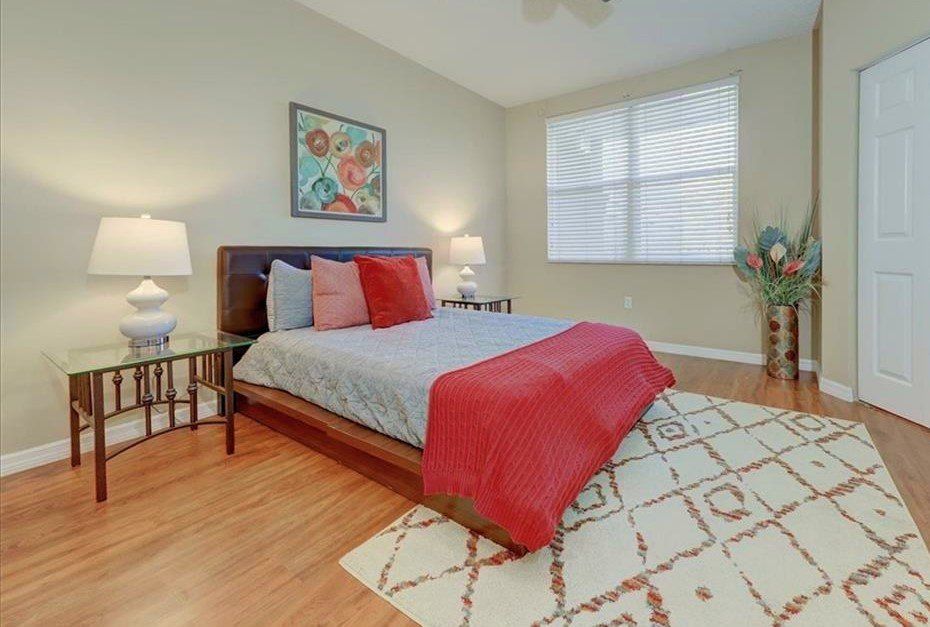 A bedroom with a bed , lamps , a rug and a window.