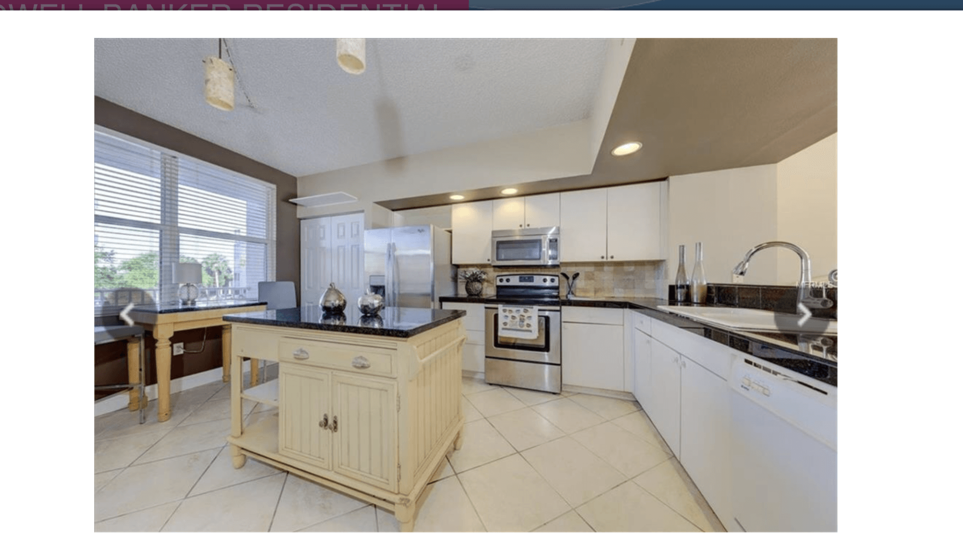 A kitchen with white cabinets , stainless steel appliances , and a large island.
