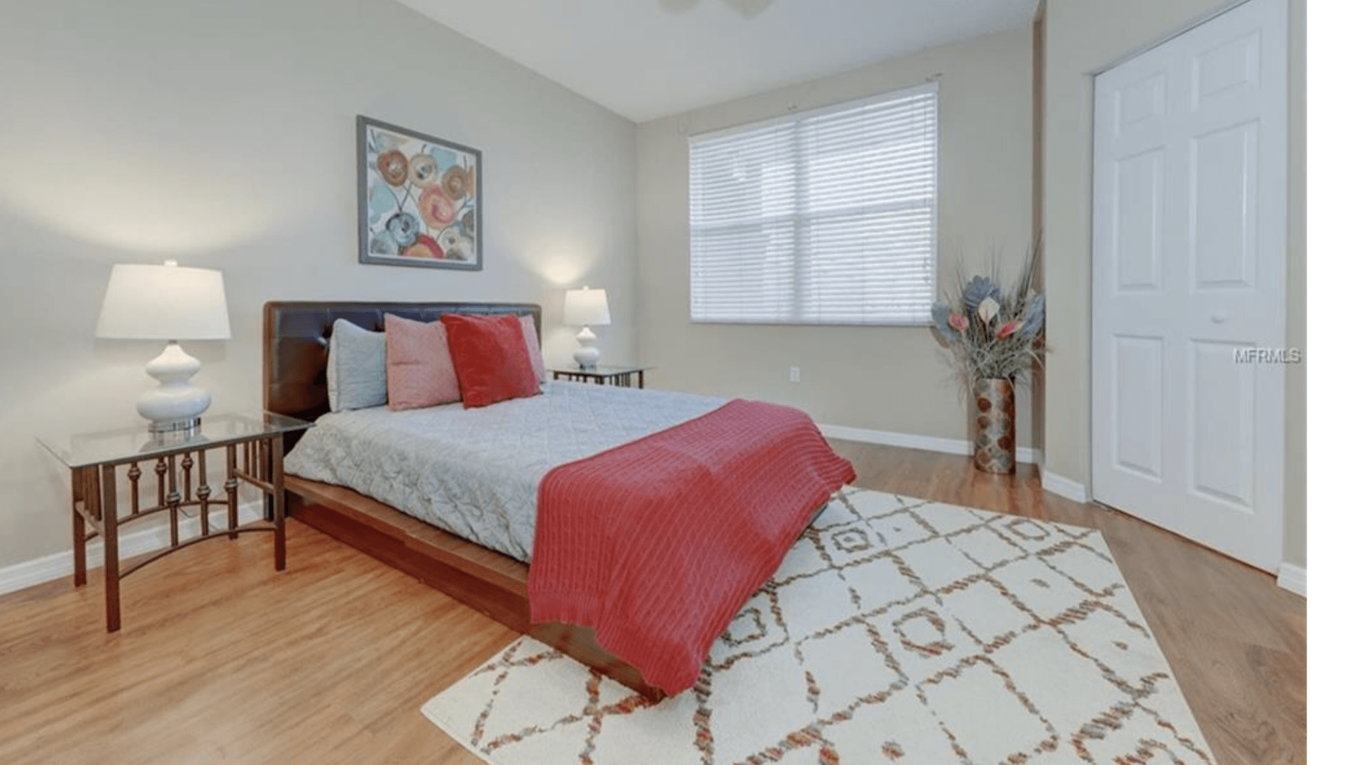 A bedroom with a bed , nightstand , lamps and a rug.