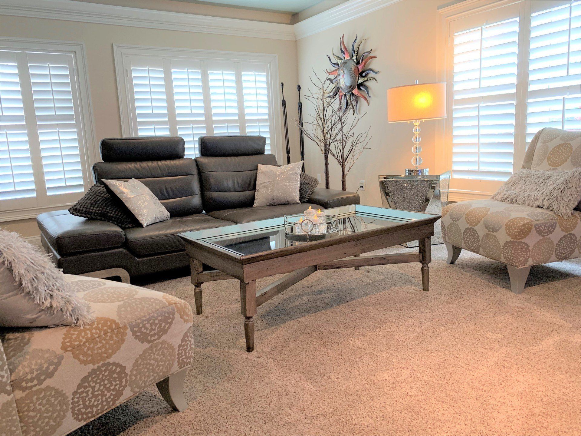 A living room with a couch , chairs , coffee table and shutters.