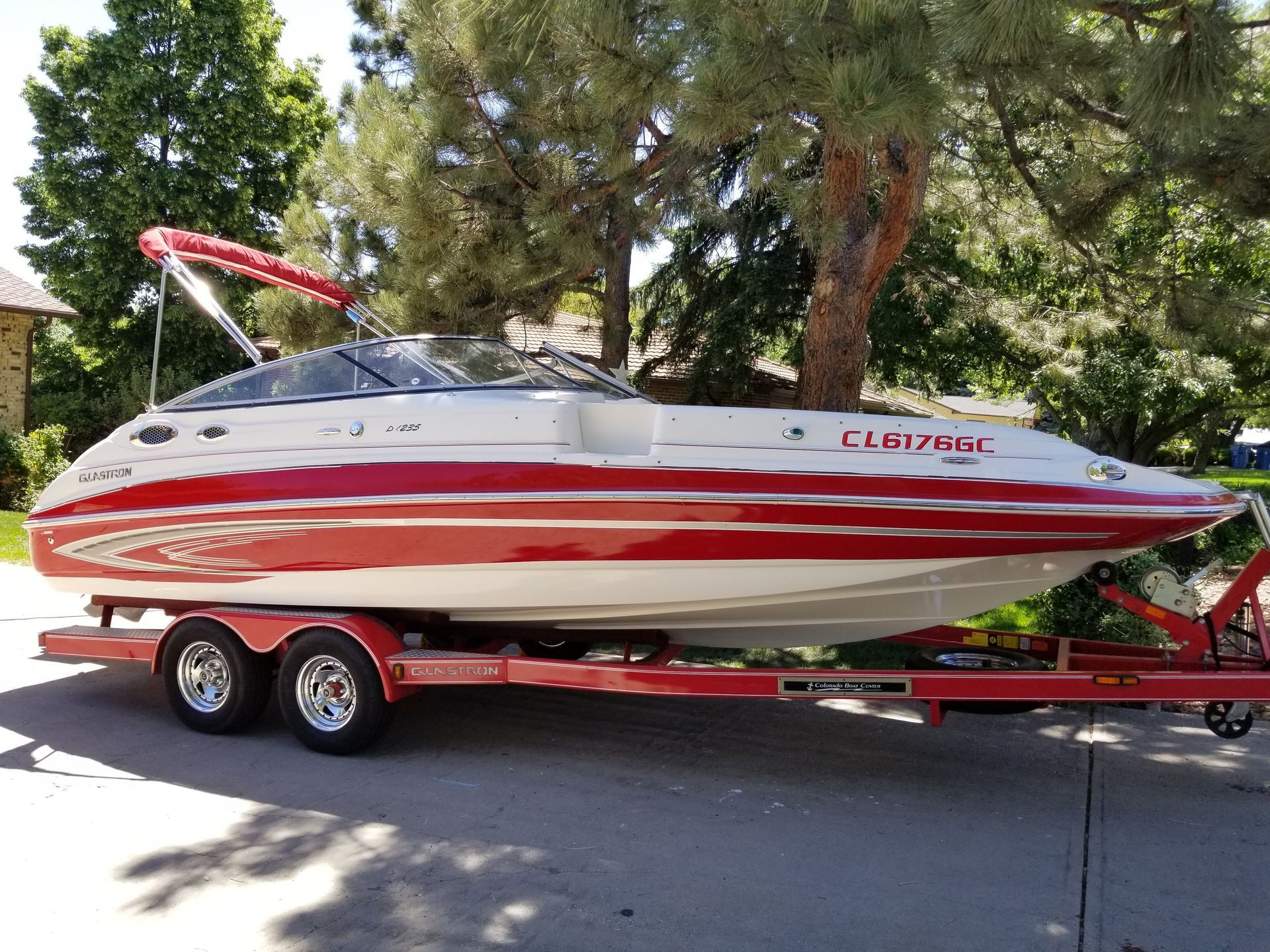 A red and white boat is parked on a trailer.