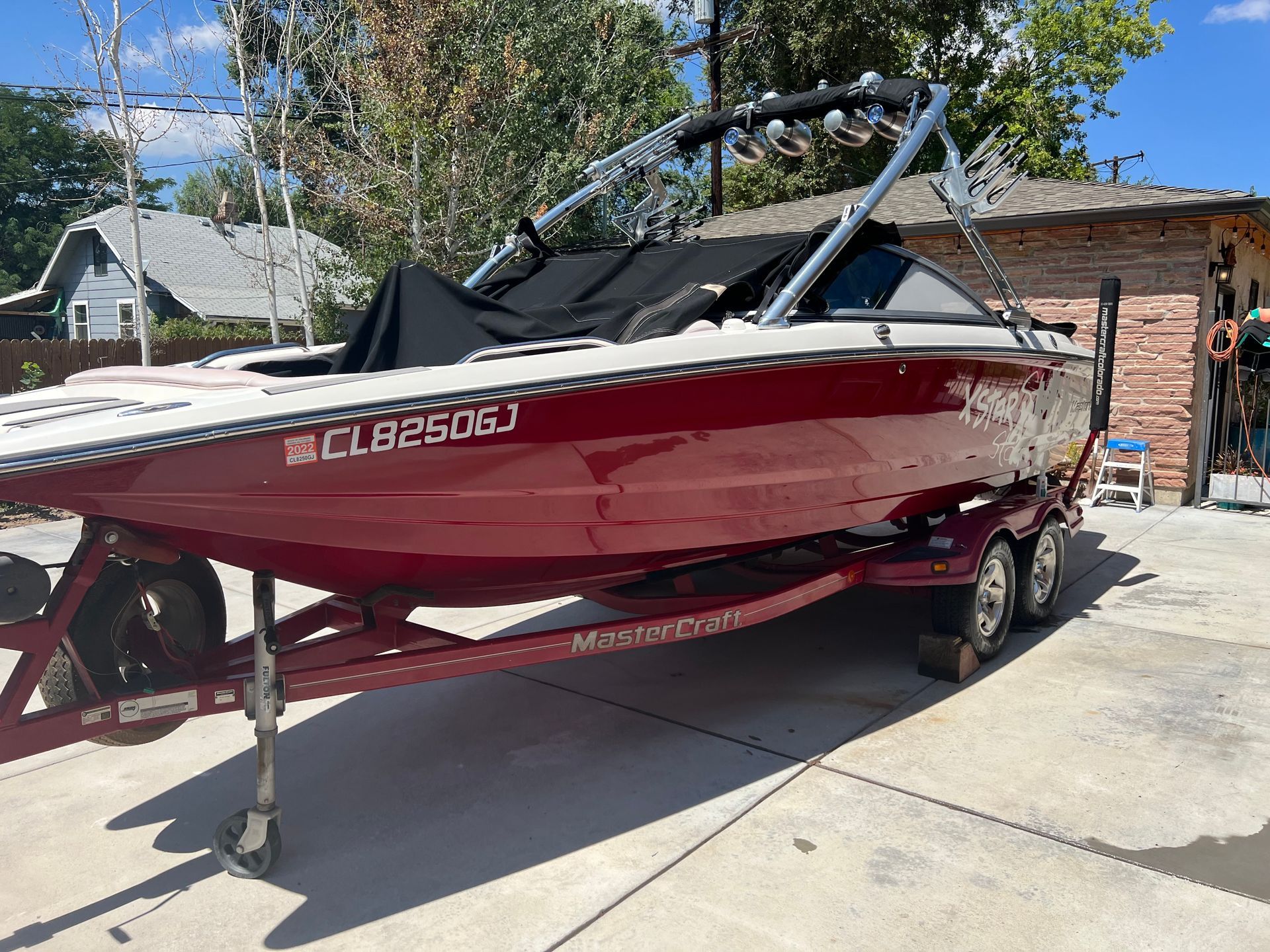A red boat is parked in a driveway next to a brick building.