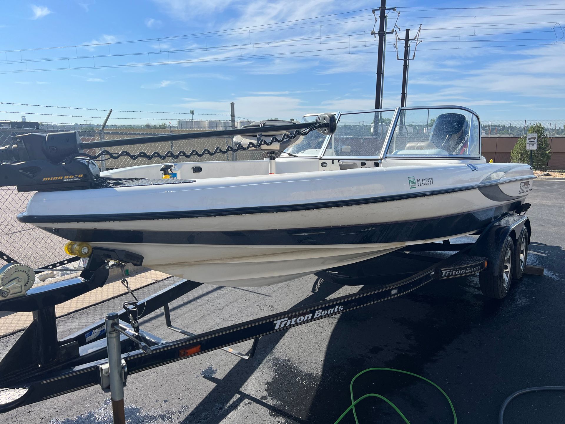 A white boat is on a trailer in a parking lot.