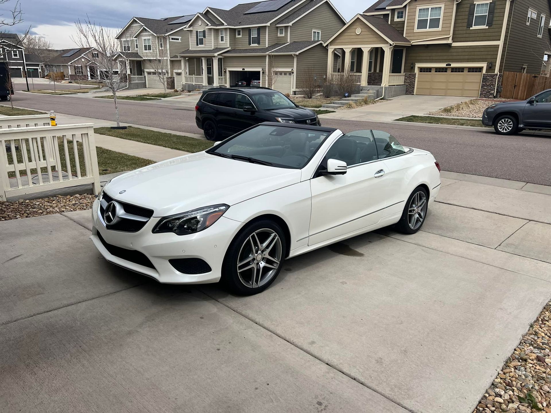 A white mercedes benz convertible is parked in a driveway.