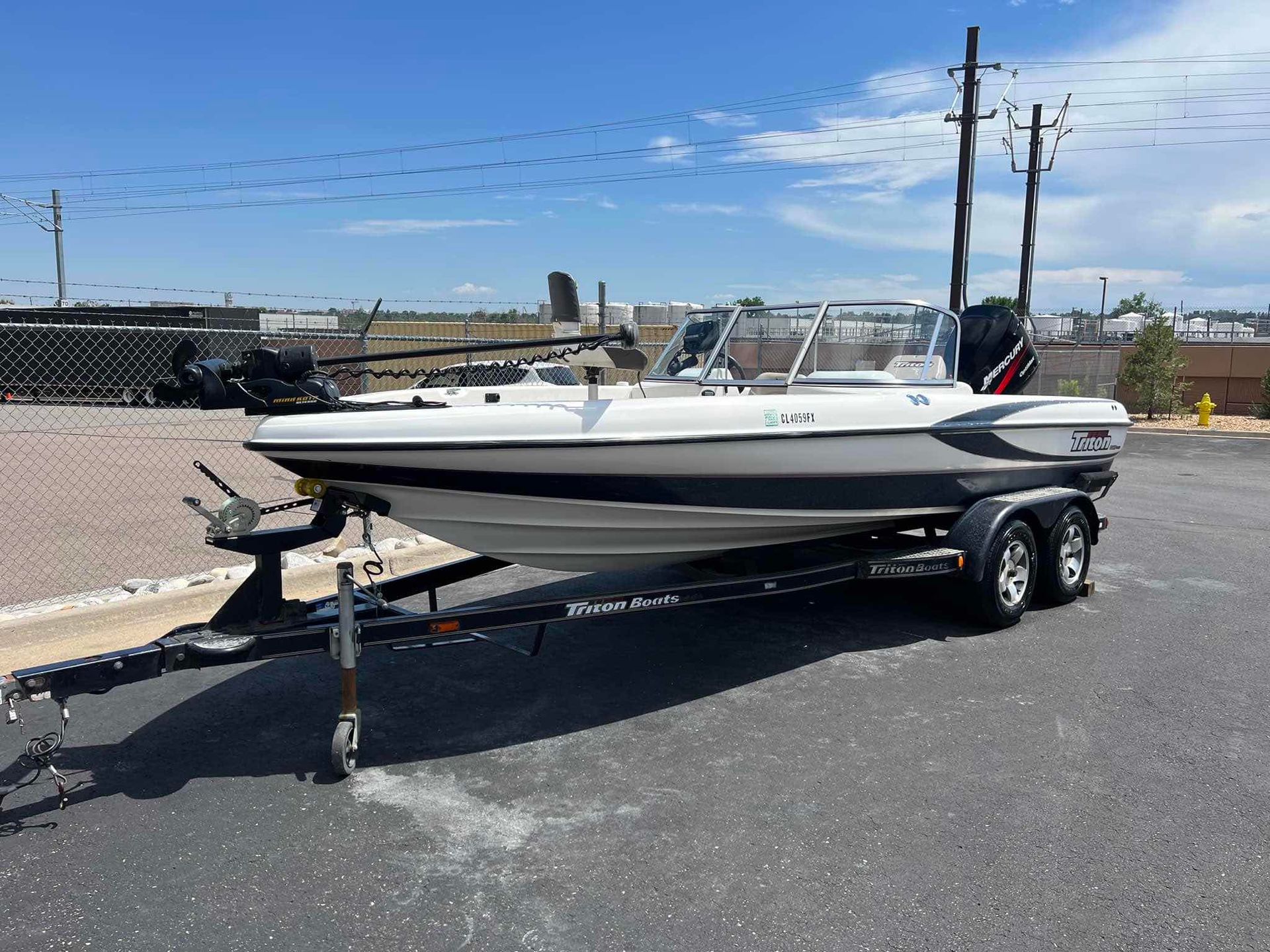 A white boat is parked on a trailer in a parking lot.