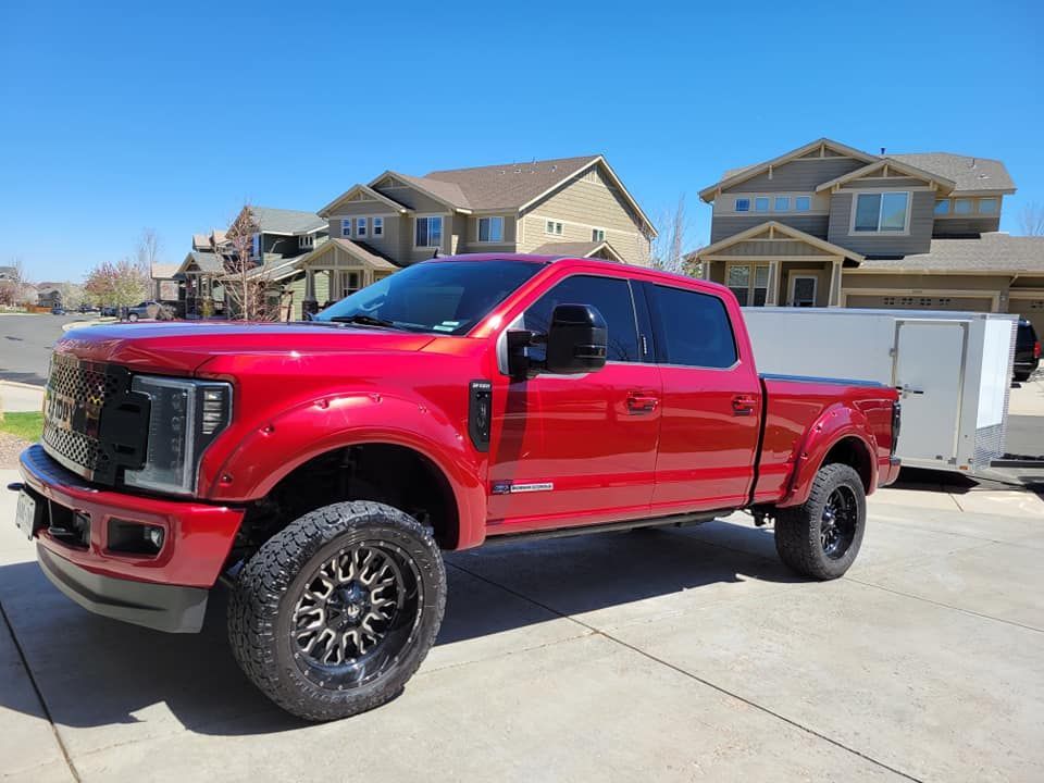A red truck is parked in a driveway in front of a house.
