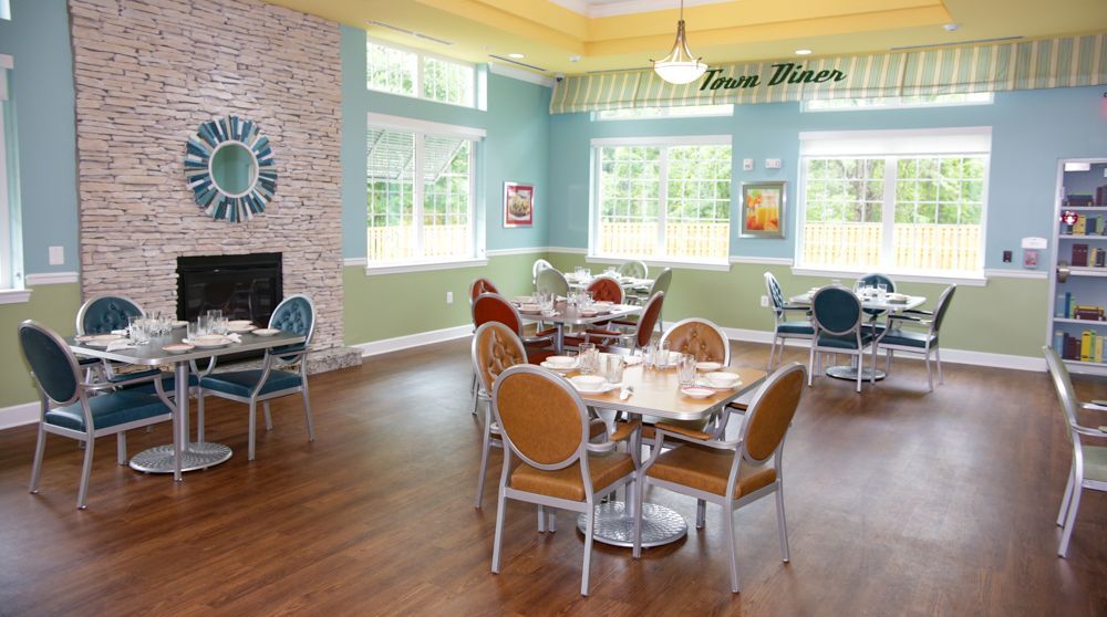 A large dining room with tables and chairs and a fireplace.