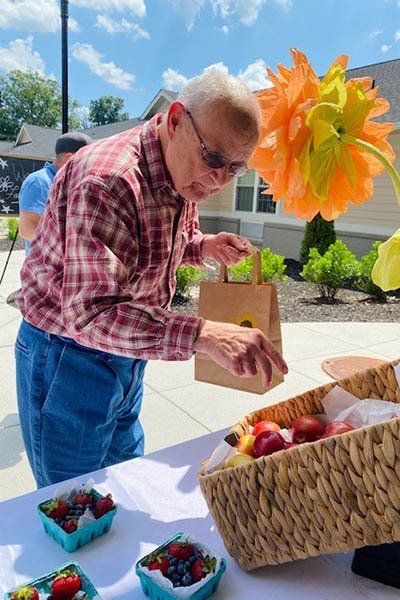 A man is standing at a table looking at a basket of fruit.