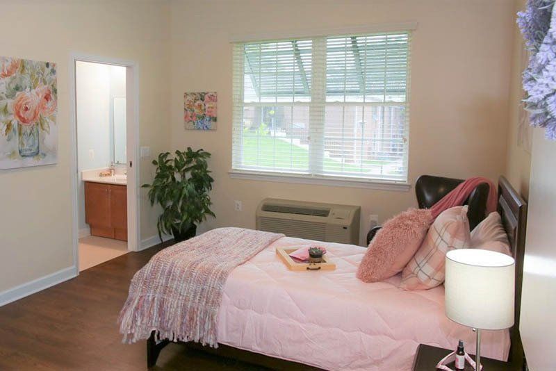 A bedroom with a bed , lamp , and window.