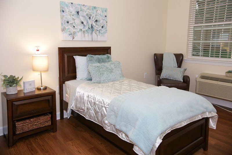 A bedroom with a single bed , nightstand , chair and window.