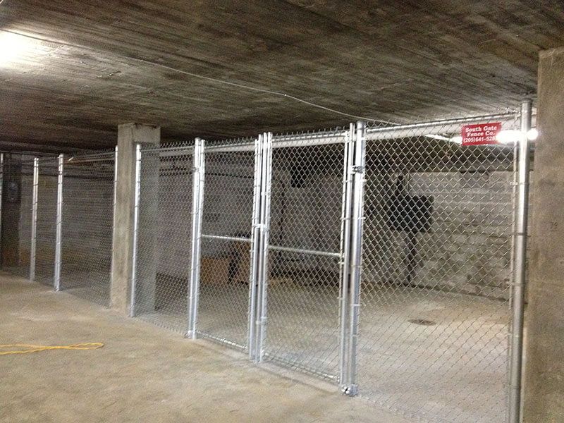 A chain link fence is surrounding a brick wall in a garage.