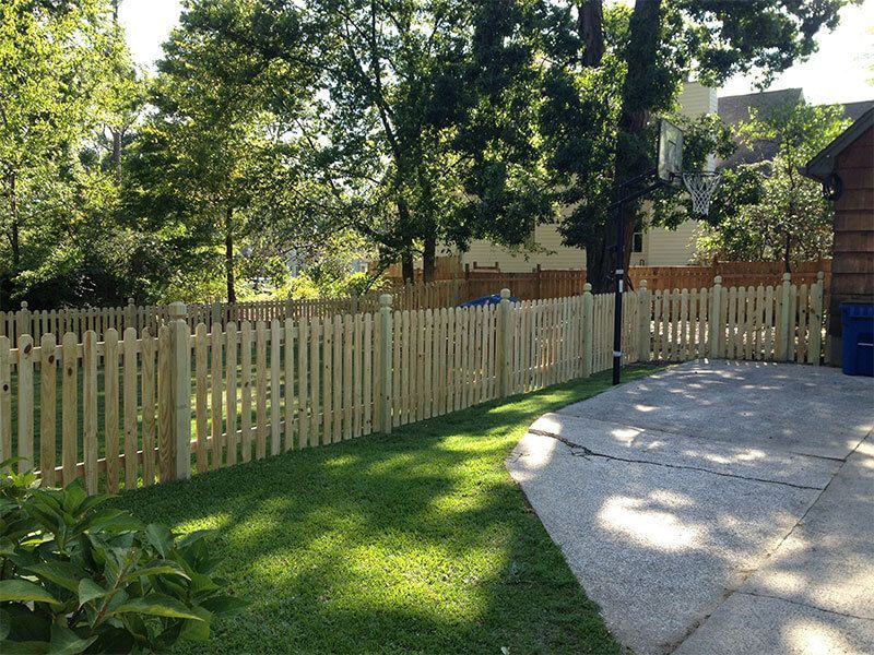 A wooden picket fence surrounds a lush green yard.