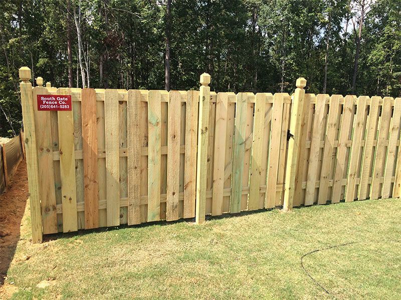 A wooden fence is sitting on top of a lush green field.