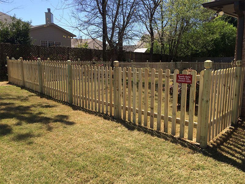 A wooden picket fence surrounds a lush green yard.