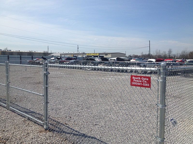A chain link fence surrounds a gravel parking lot