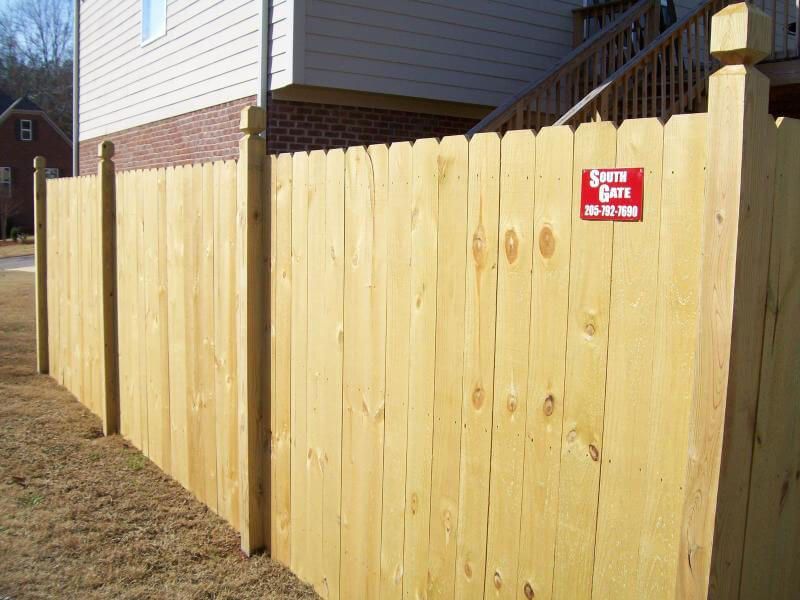 A wooden fence is sitting in front of a house.