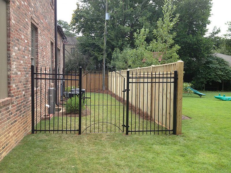 A backyard with a wooden fence and a metal gate