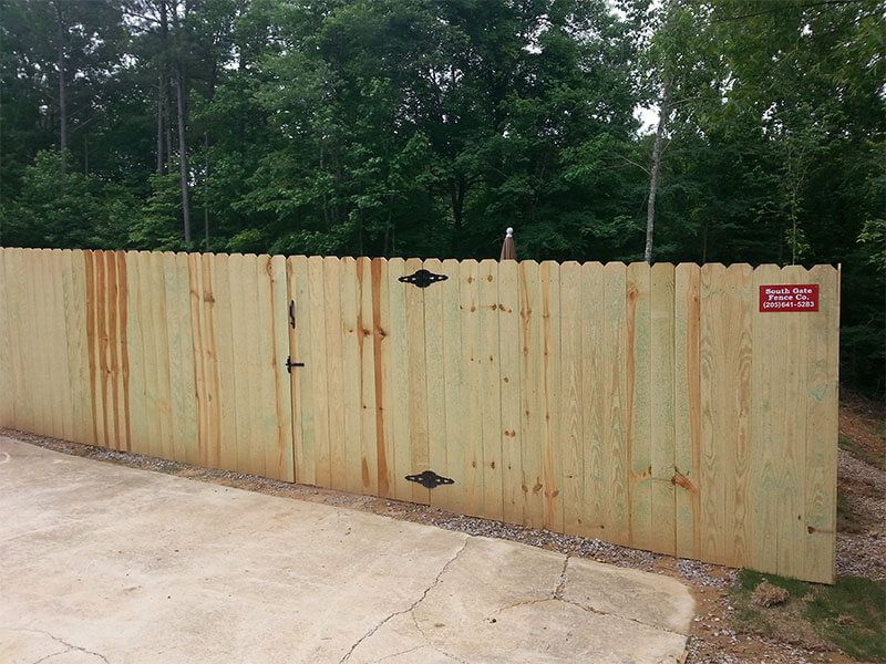 A wooden fence with a gate and a sign that says 