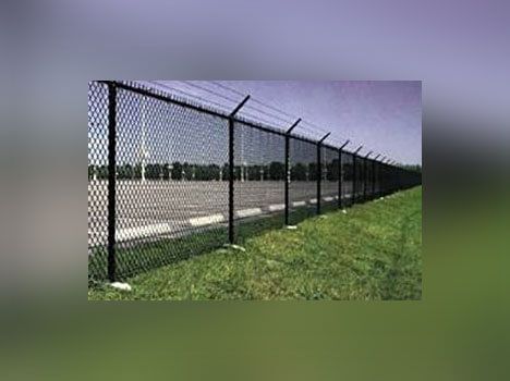 A chain link fence surrounds a grassy field.