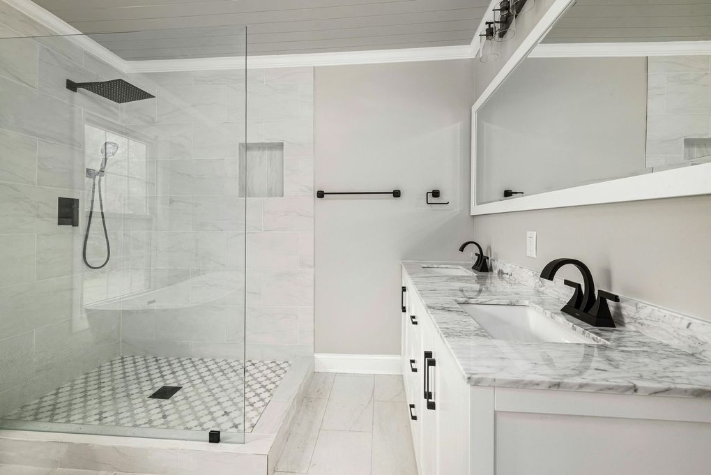 A bathroom with a walk in shower , sink and mirror.