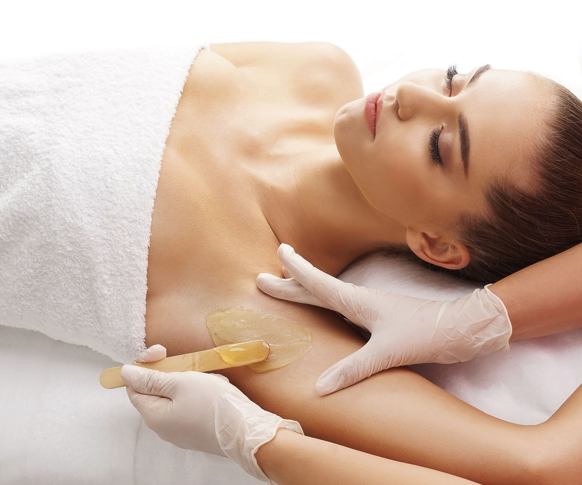 Woman receiving underarm waxing treatment at a spa.