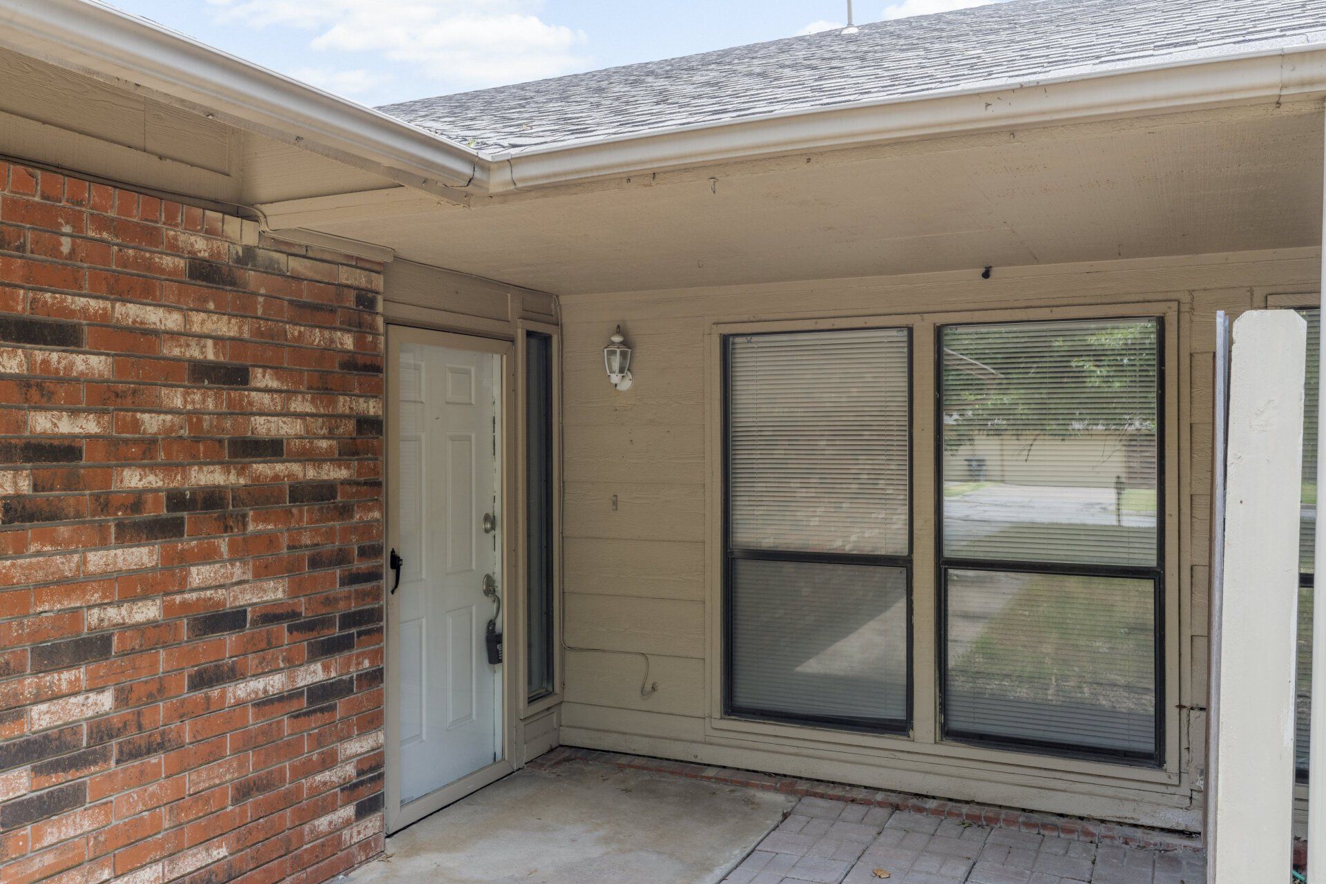 A brick house with a white door and two windows.