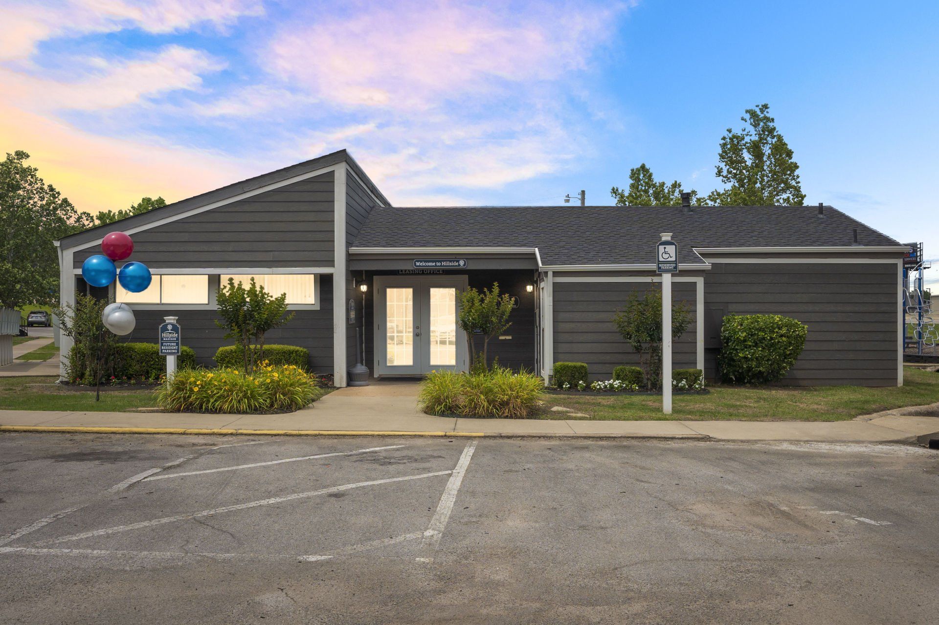 A house with balloons in front of it and a parking lot in front of it.