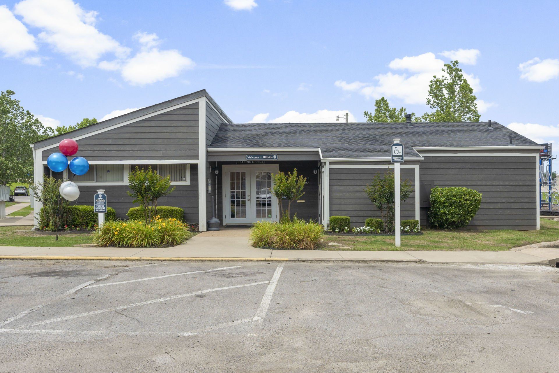 A house with balloons in front of it and a parking lot in front of it.