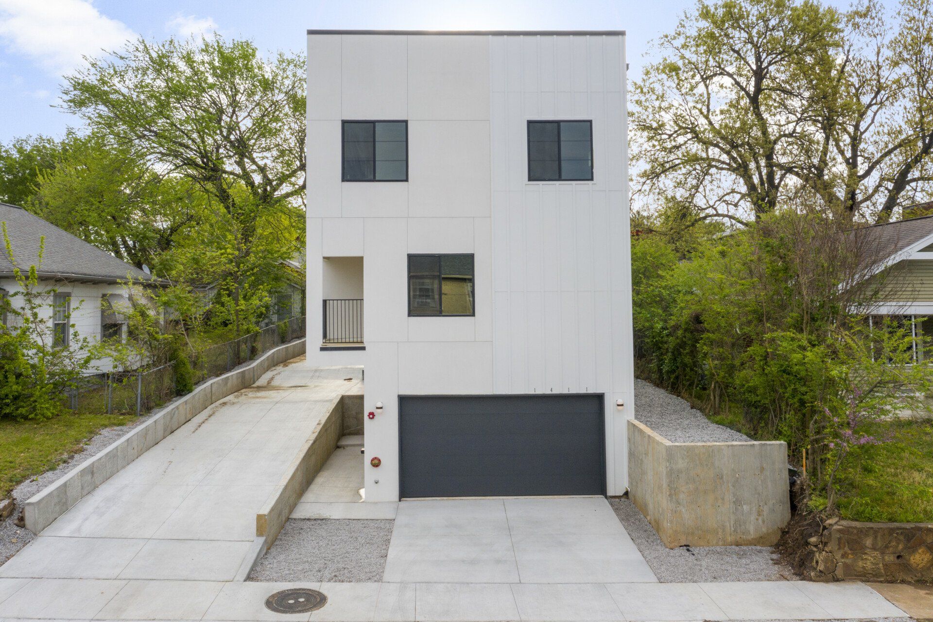 A white house with a black garage door and a ramp leading to it.