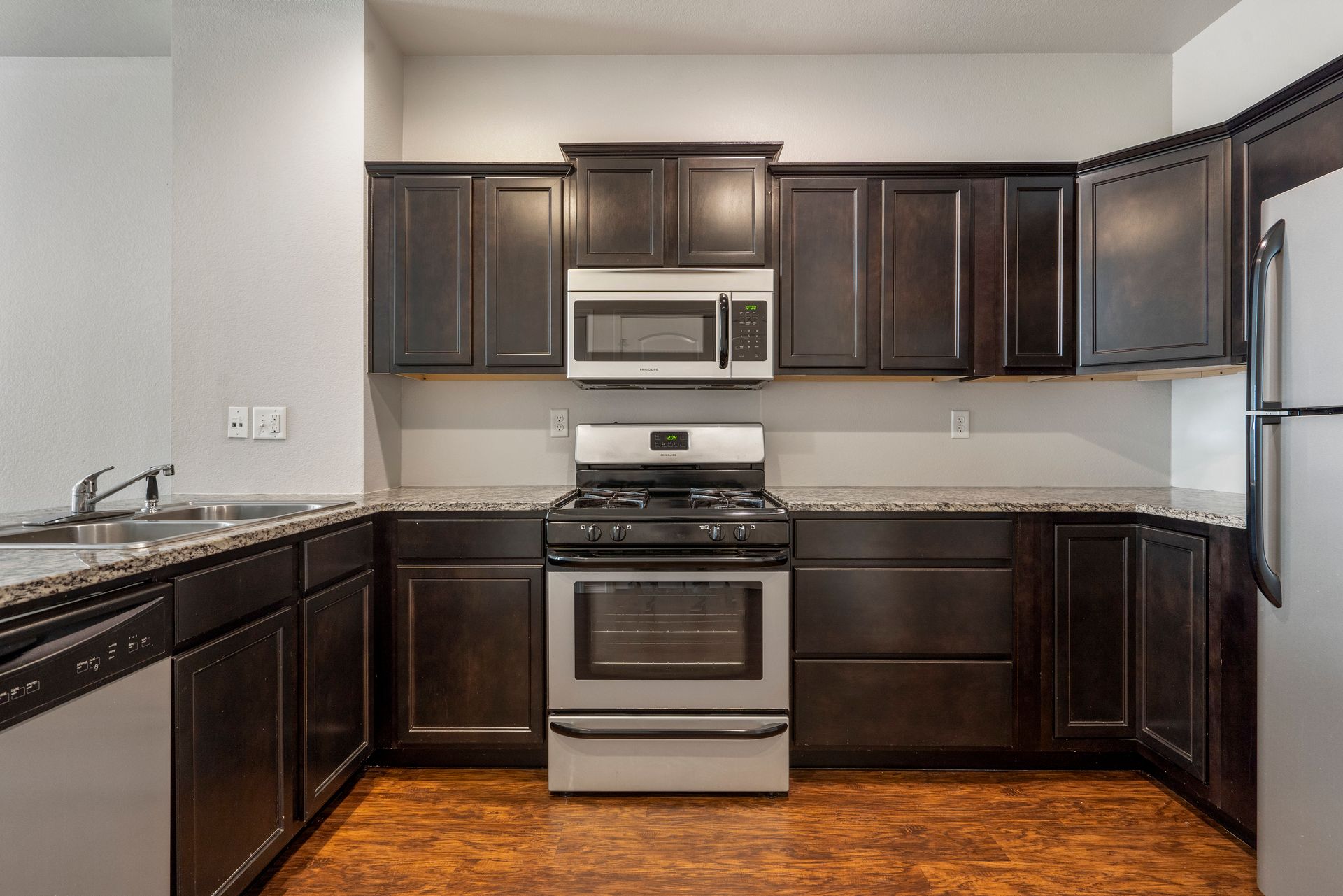 A kitchen with a stove , microwave , refrigerator , sink and dishwasher.