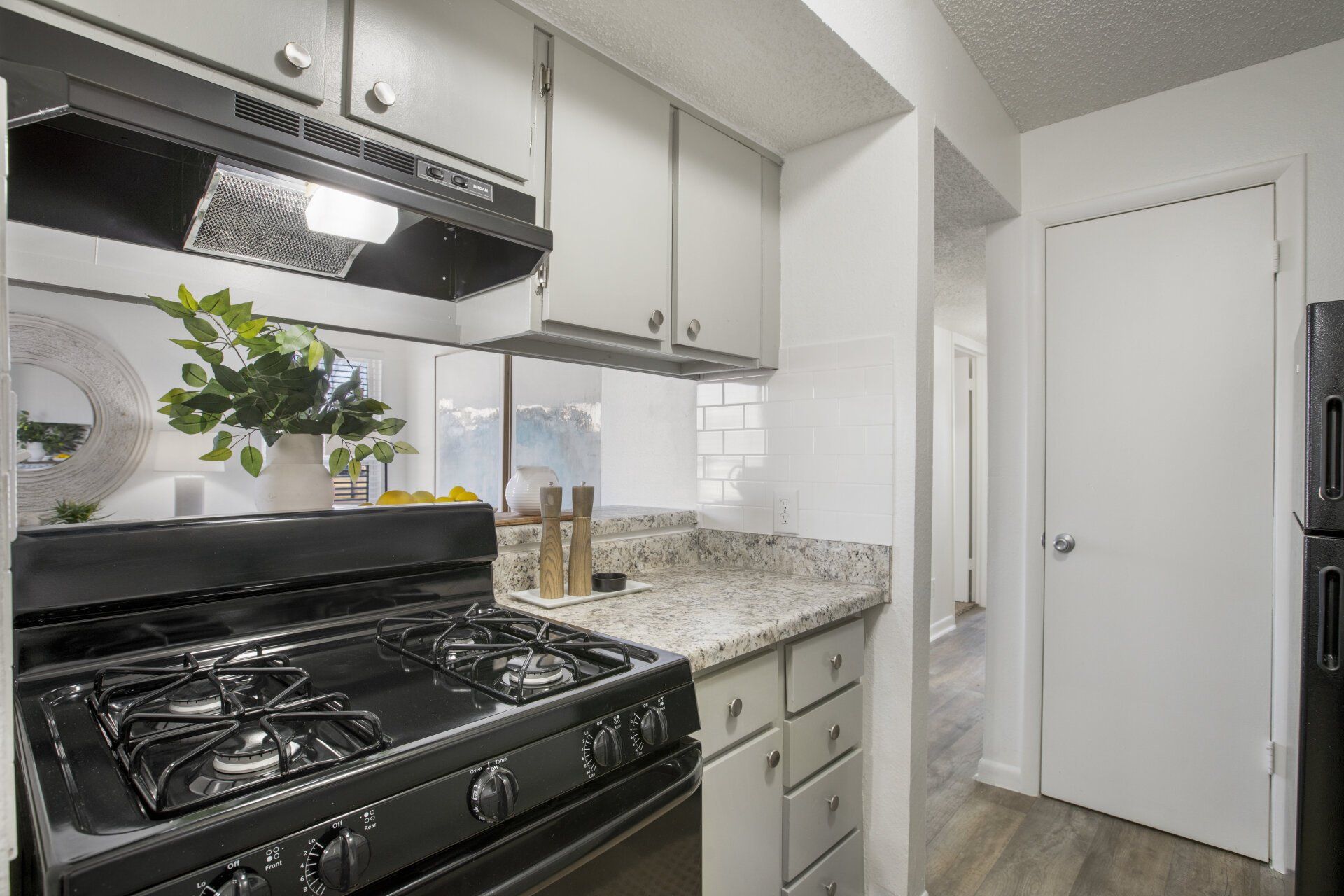 A kitchen with a stove , refrigerator , and cabinets.