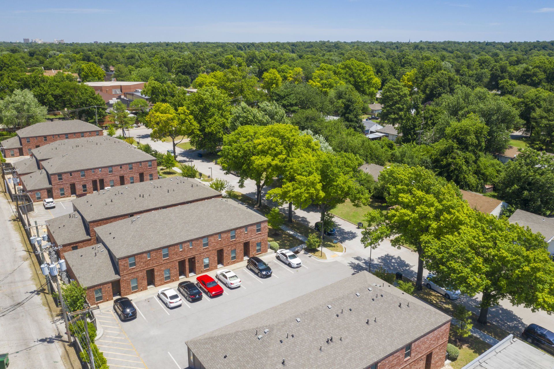 An aerial view of a row of apartment buildings with cars parked in front of them.