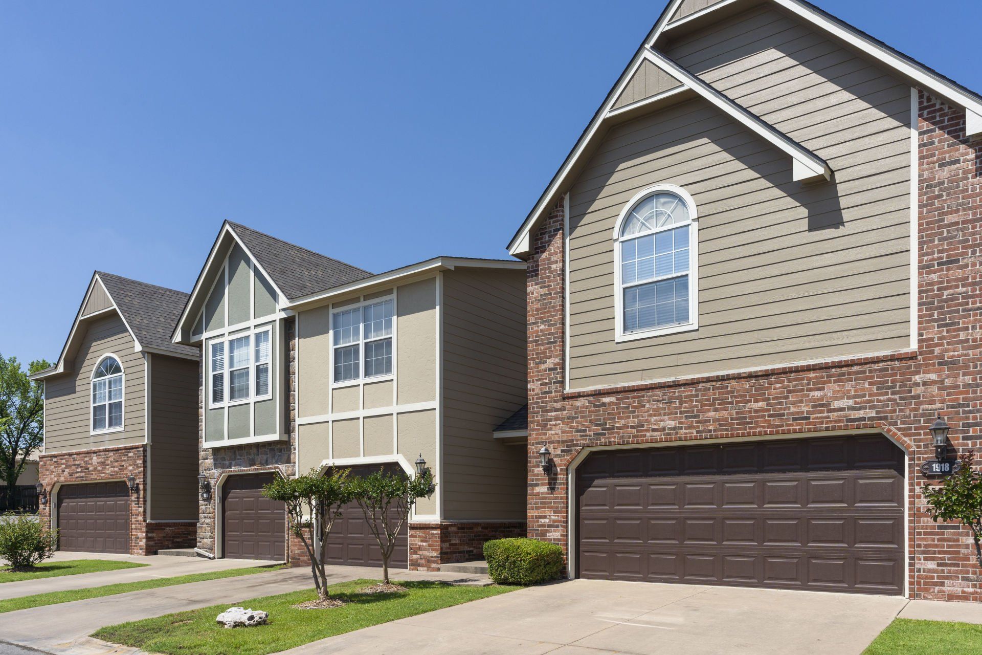 A row of houses with brown garage doors on a sunny day