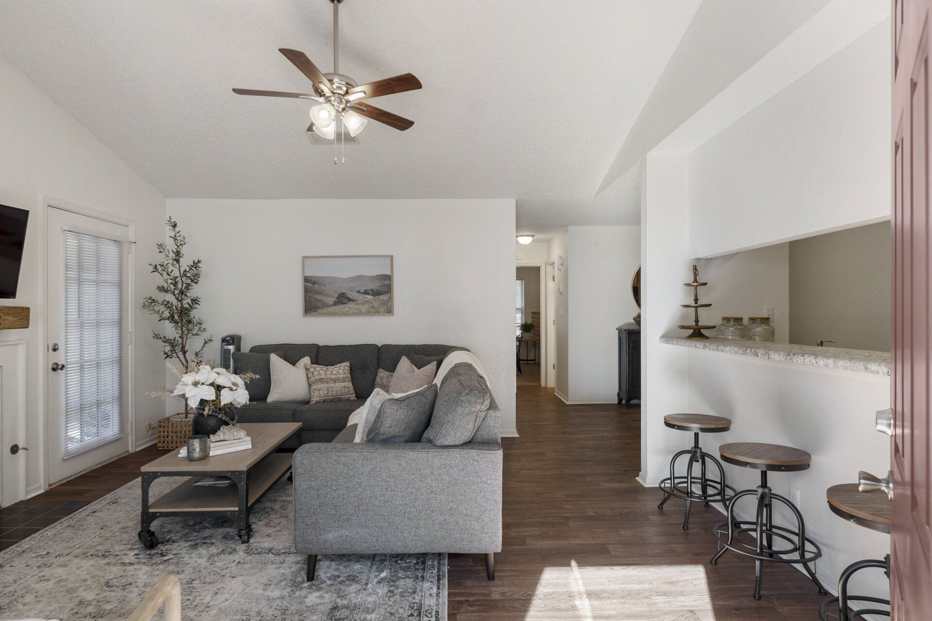 A living room with a couch , coffee table , stools and a ceiling fan.