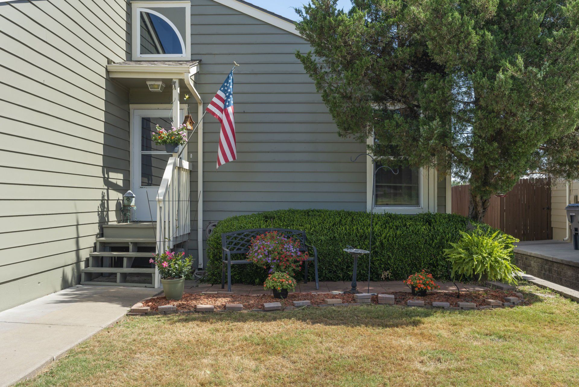 The front of a house with an american flag hanging from the porch.