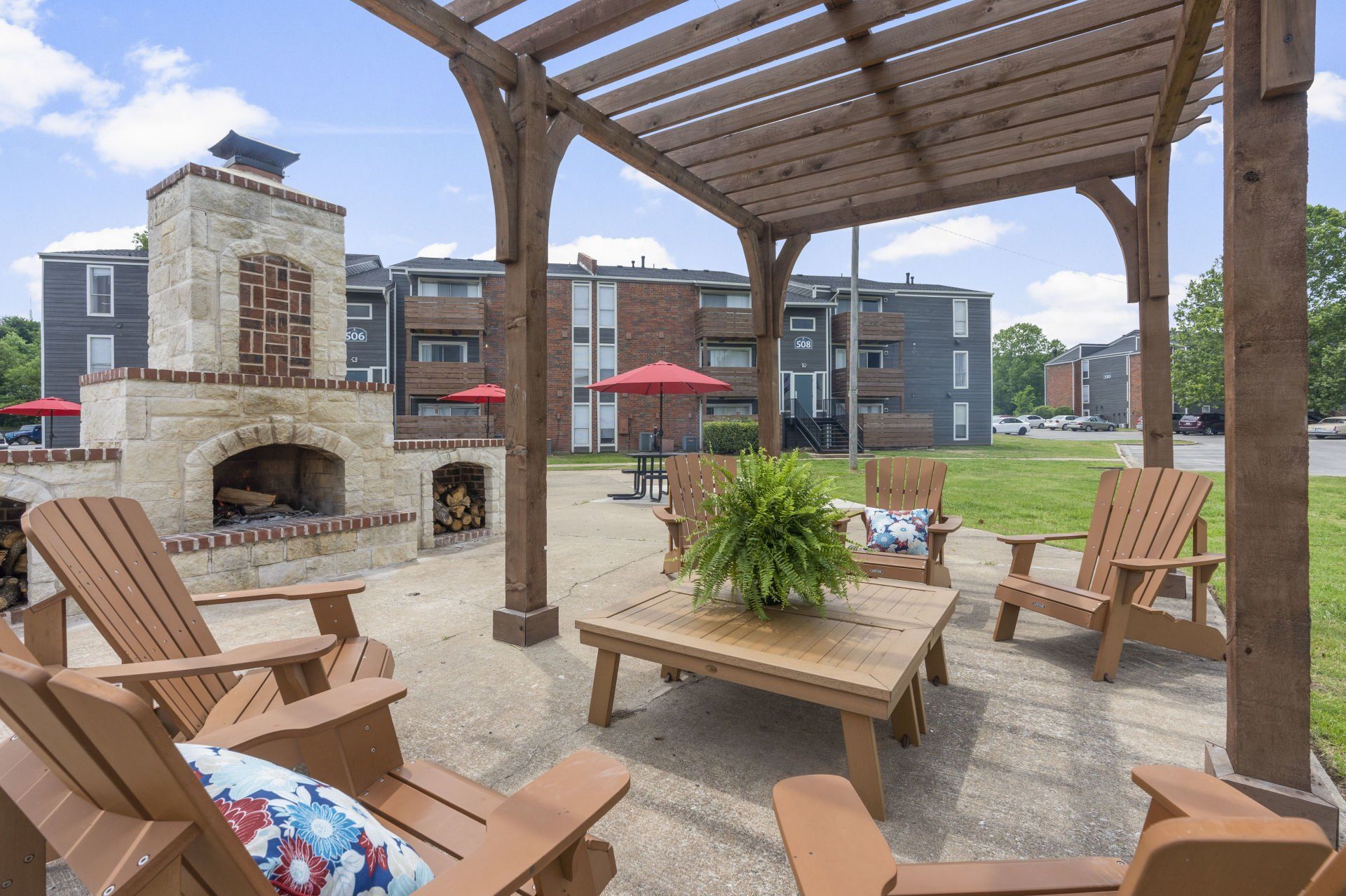 A patio with chairs , a table and a fireplace under a pergola.