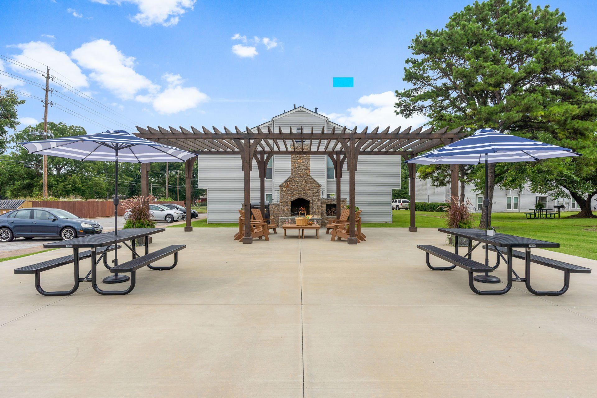 A picnic area with tables and umbrellas and a fireplace.