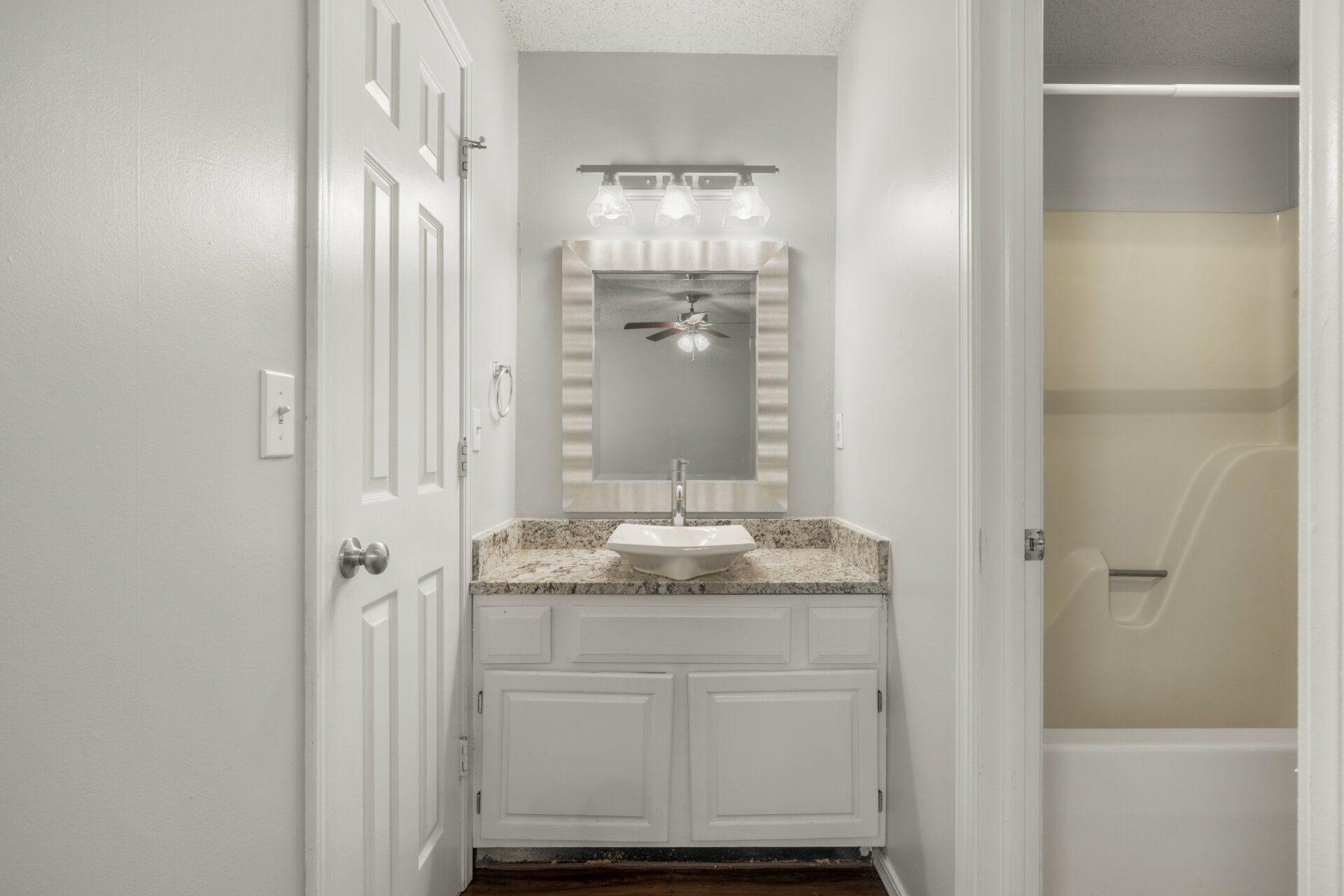 A bathroom with a sink , mirror , tub and shower.